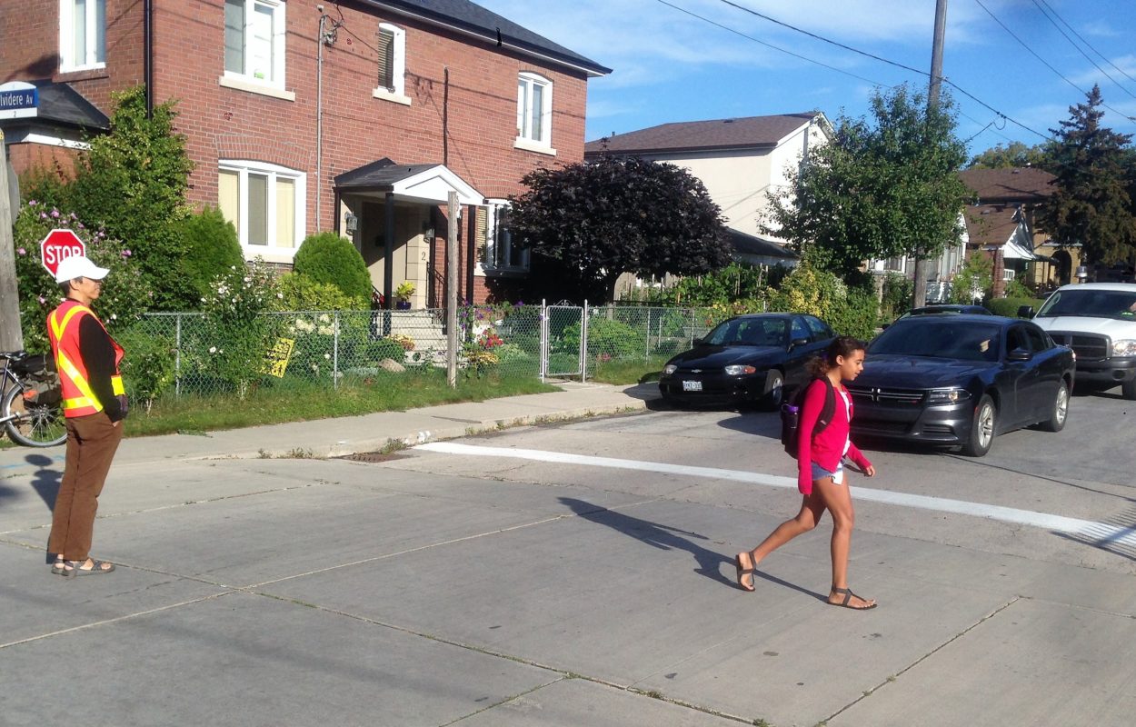 Child crossing the street, with crossing guard