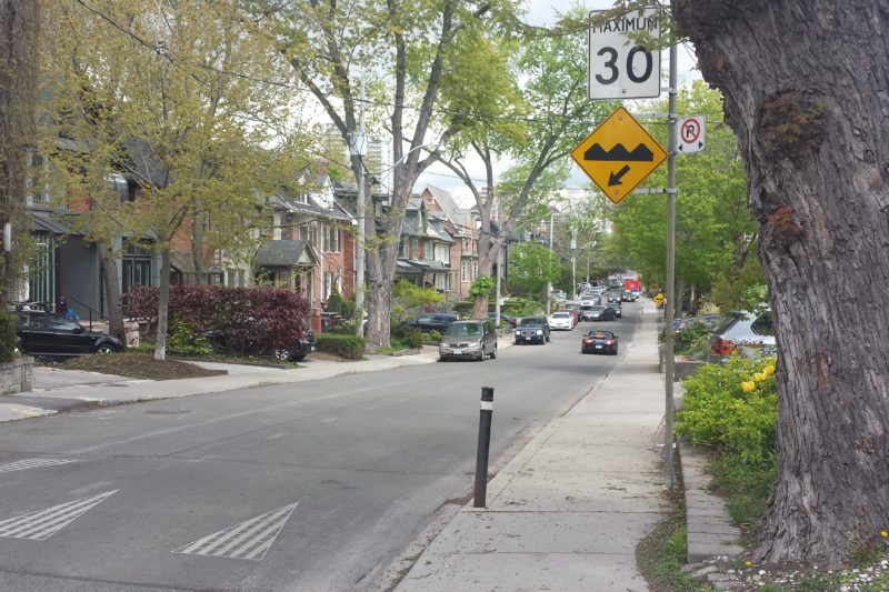Picture of a residential street in Toronto with speed bumps and a sign that shows a speed limit of 30 kilometre per hour