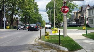 A picture of an intersection in a residential neighbourhood with curb extensions and stop signs.