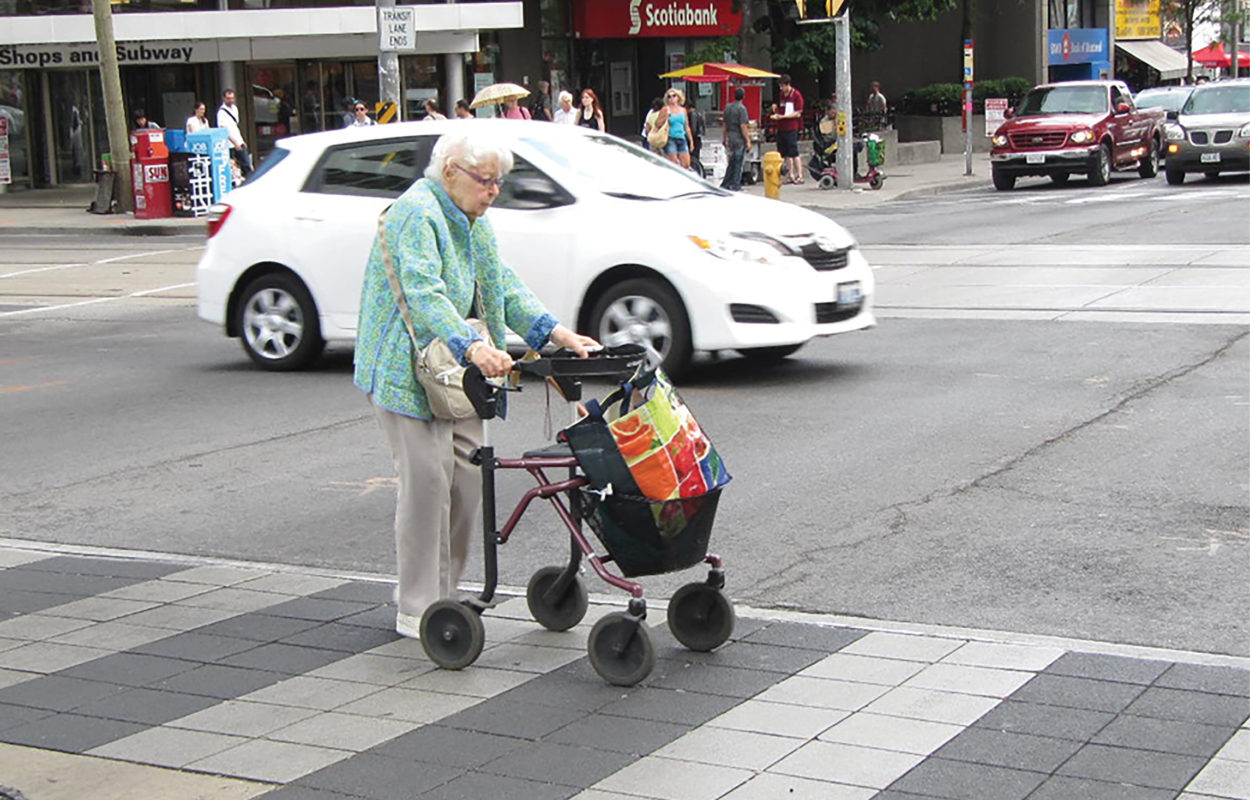 Senior with walker crossing the street in a crosswalk